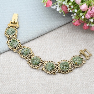 Puede incluir: Pulsera vintage dorada con siete cabujones redondos de piedra verde. Cada piedra está engastada en un marco floral. La pulsera tiene un cierre de broche. Diseño clásico de joyería.