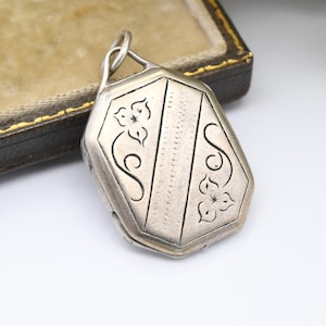 May include: A silver locket with an octagonal shape and an engraved design of stylized flowers and swirls.