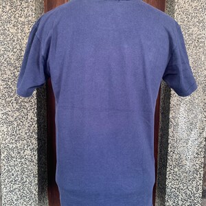 May include: A solid navy blue short-sleeved t-shirt. The shirt is made of a soft, slightly textured fabric. The neckline and sleeves have a worn appearance.
