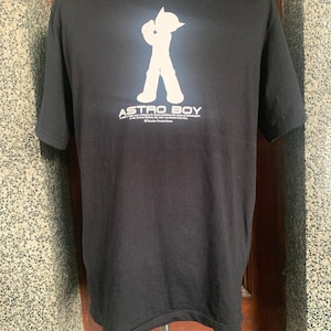 May include: Black t-shirt with a white silhouette of Astro Boy, the text "ASTRO BOY" and the copyright information "© Tezuka Productions".