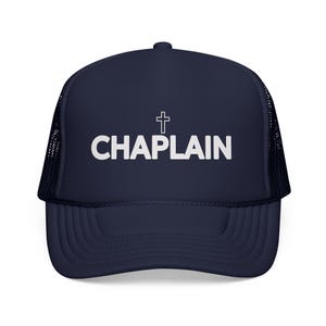 May include: Navy blue trucker hat with the word "CHAPLAIN" in white block letters and a white cross above the text. The hat has a curved brim and a mesh back.