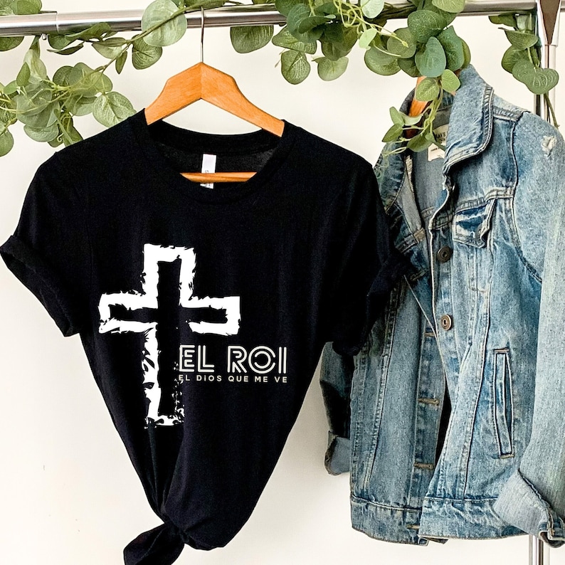 May include: Black t-shirt with a white cross and the text "El Roi El Dios Que Me Ve" printed on the front.