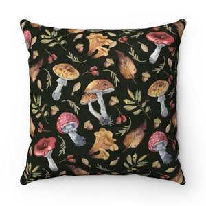 May include: A black throw pillow with a watercolor pattern of mushrooms, leaves, and berries. The mushrooms are red, yellow, and brown.