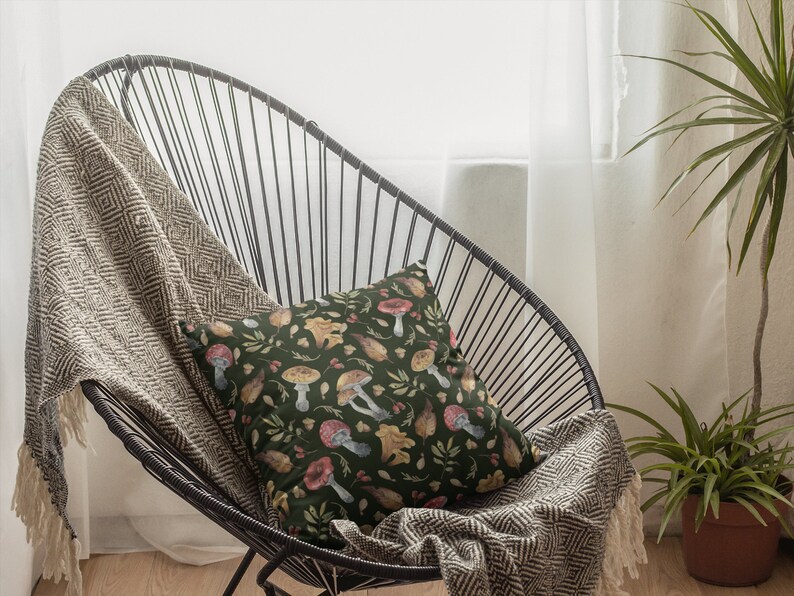 May include: A black metal chair with a brown and white throw blanket and a green pillow with a mushroom and leaf pattern.