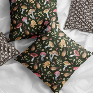 May include: Two throw pillows with a green background and a pattern of mushrooms, leaves, and berries. One pillow has a brown and white geometric pattern.