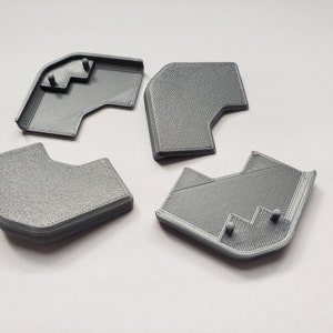 May include: Four gray plastic corner pieces, likely for a shelf or furniture assembly.