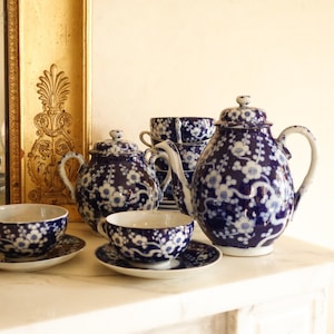 May include: A blue and white porcelain tea set with a floral pattern. The set includes a teapot, creamer, sugar bowl, and two teacups and saucers.