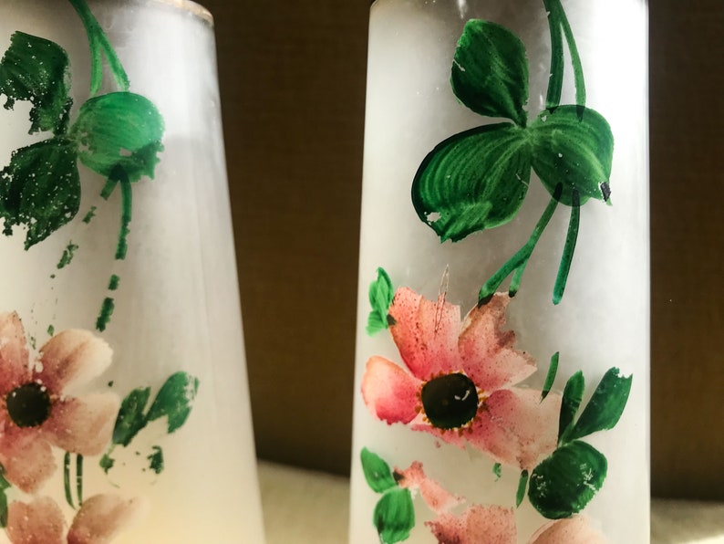 Peut inclure: Deux sali&egrave;res et poivri&egrave;res en verre givr&eacute; avec des fleurs roses et des feuilles vertes peintes &agrave; la main.