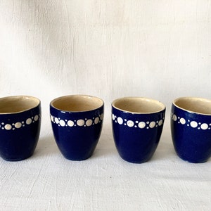 May include: Four blue ceramic egg cups with white polka dot trim.