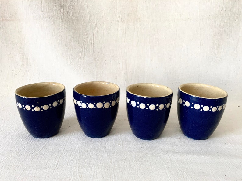May include: Four blue ceramic egg cups with white polka dot trim.