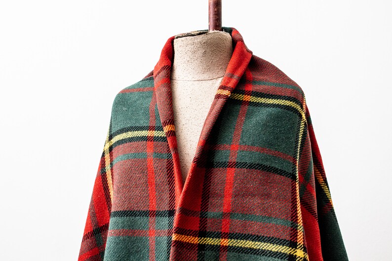 May include: A red, green and yellow plaid throw blanket draped over a mannequin.