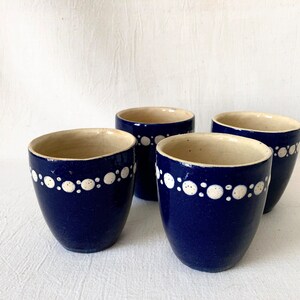 May include: Four blue ceramic mugs with white polka dot designs around the rim.