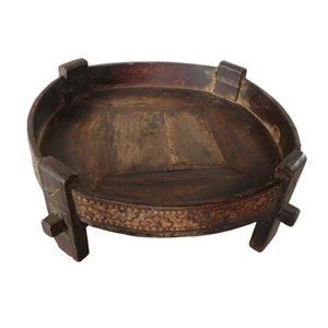 May include: A round wooden tray with a carved design around the edge. The tray is supported by four legs and has a dark brown finish.