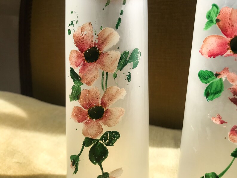 Peut inclure: Deux bouteilles en verre givr&eacute; avec des motifs floraux roses et verts. Les bouteilles sont transparentes et ont une surface textur&eacute;e.