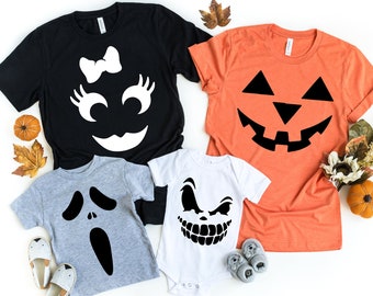 May include: A set of four Halloween-themed t-shirts featuring different jack-o'-lantern faces. The shirts are in black, grey, white, and orange.