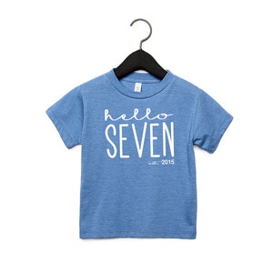 Peut inclure: Un t-shirt bleu &agrave; manches courtes avec du texte blanc qui dit "hello seven est. 2015".