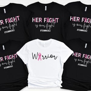 May include: Five black t-shirts with pink ribbon graphics and the text "HER FIGHT is our fight #TEAMNICOLE" and one white t-shirt with a pink ribbon graphic and the text "Warrior".