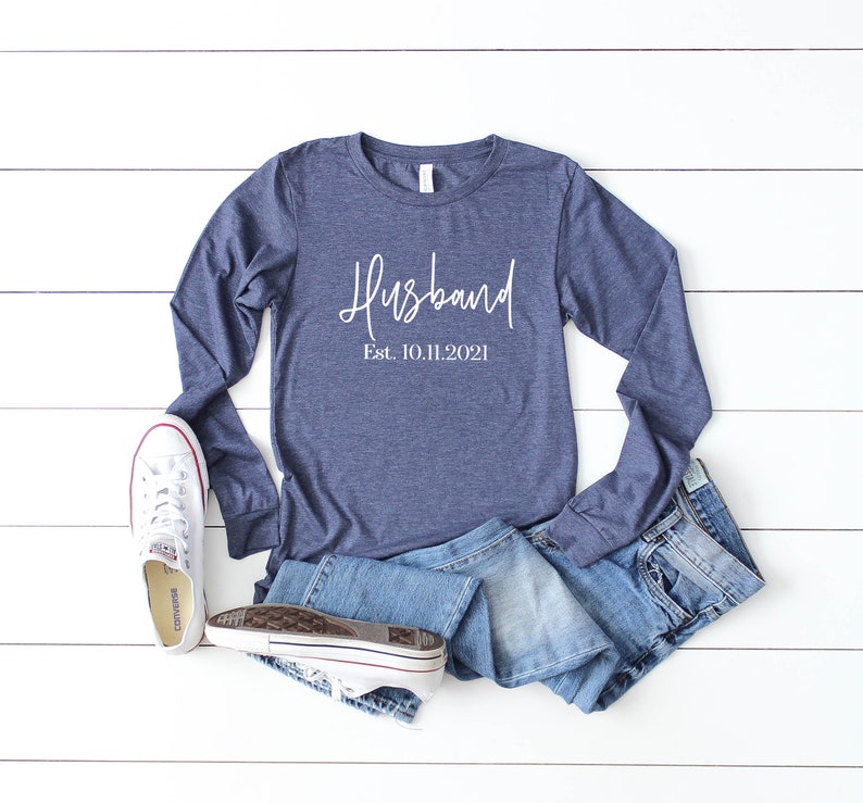 Puede incluir: Una camiseta de manga larga azul marino con el texto "Husband Est. 10.11.2021" en letras blancas.