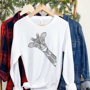 May include: White long-sleeve t-shirt with a black and white illustration of a giraffe's head peeking out from the side.