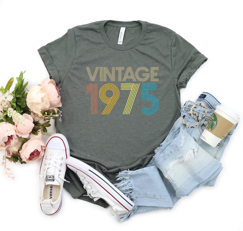 May include: A green t-shirt with the text "Vintage 1975" in rainbow colors. The text is in a retro font style.