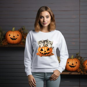 a woman standing in front of pumpkins with cats on them