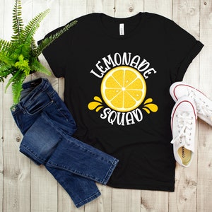 May include: Black t-shirt with a white graphic of a lemon slice and the text "Lemonade Squad".