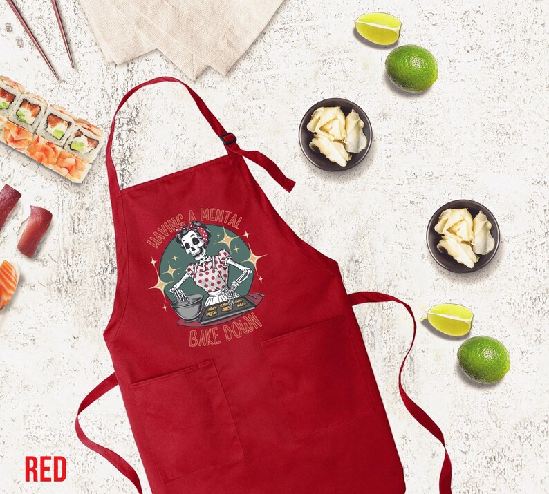 May include: Red kitchen apron with a skeleton baking and the text "Having a mental bake down".