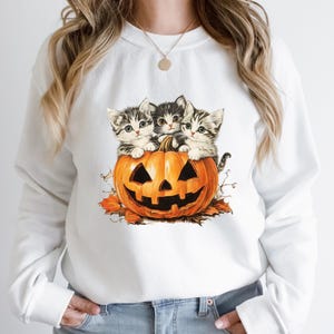 a woman wearing a white sweatshirt with kittens on it