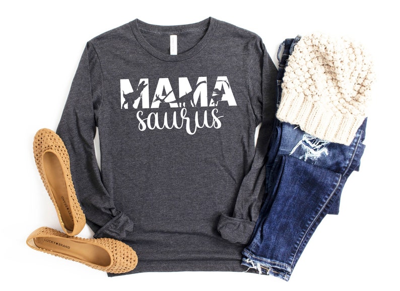 May include: A dark grey long-sleeved shirt with the text "Mama saurus" in white. The text is surrounded by a silhouette of dinosaurs.