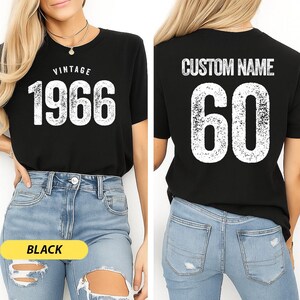 A woman wearing a black t-shirt with the text "VINTAGE 1966" printed on it, along with the number "60" printed below. She is also wearing distressed jeans.