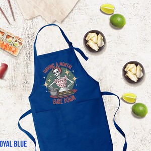May include: Royal blue kitchen apron with a skeleton baking and the text "Having a mental bake down".