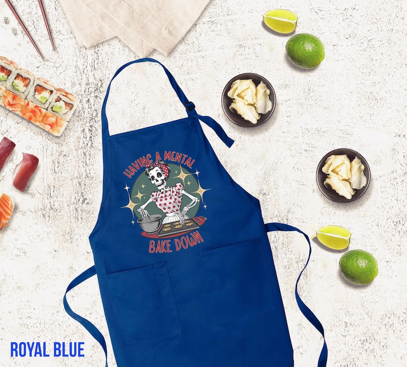 May include: Royal blue kitchen apron with a skeleton baking and the text "Having a mental bake down".