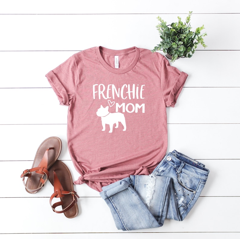 May include: A pink t-shirt with the text "Frenchie Mom" and a white silhouette of a French Bulldog.