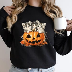 a woman holding a cup of coffee with two cats on it