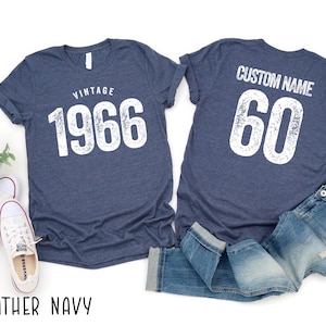 a pair of blue vintage-style t-shirts with the text "VINTAGE 1966" printed on them, along with a pair of jeans and sneakers.