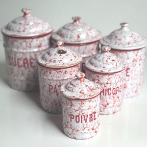 Puede incluir: Un conjunto de seis botes de cerámica blancos y rojos moteados con tapas. Los botes están etiquetados con texto rojo: SUCRE, PÂTÉ, HICORE y POIVRE. Cada tapa tiene un pequeño pomo en la parte superior.