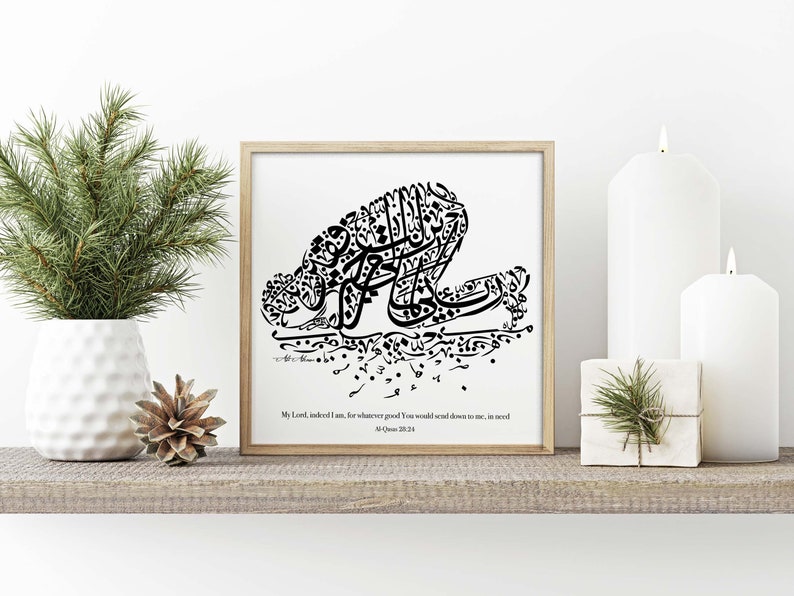 May include: A framed black and white calligraphy art print. The artwork features stylized Arabic script forming a kneeling figure. The text at the bottom reads "My Lord, indeed I am, for whatever good You would send down to me, in need".