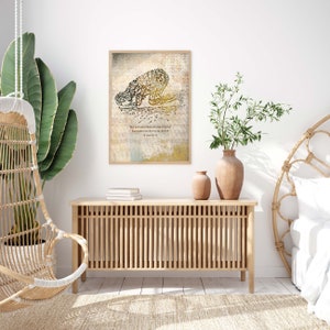 May include: A framed print featuring Arabic calligraphy in black and gold, depicting a figure in prayer. The artwork is set against a textured, neutral-toned background with a quote in English. The frame is a light wood color.