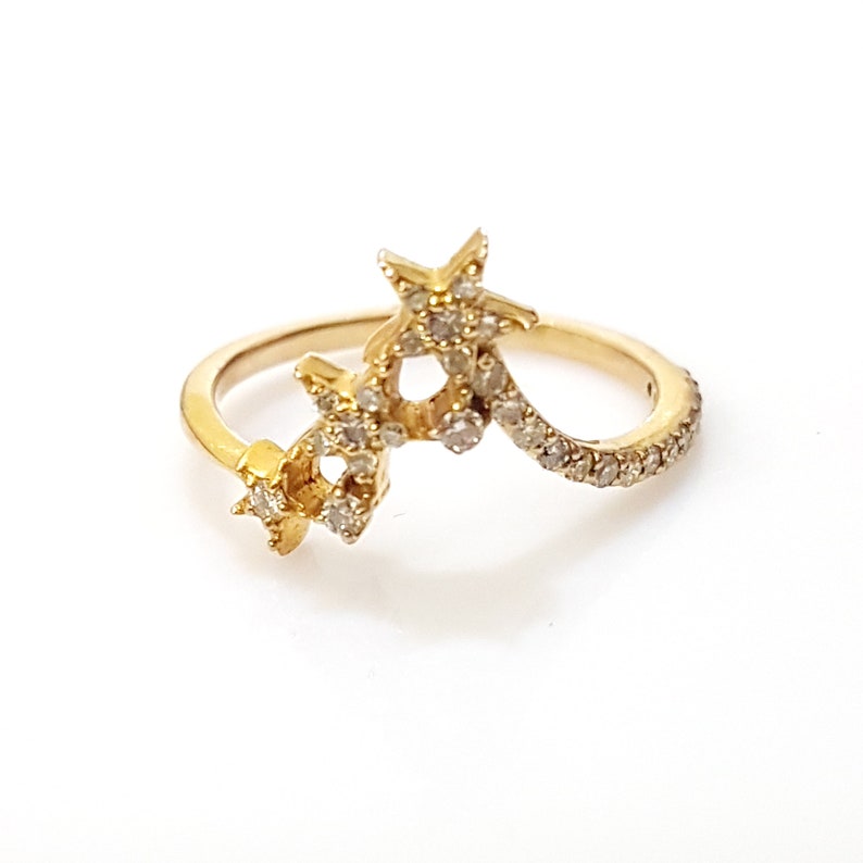 K&ouml;nnte beinhalten: Ein goldener Ring mit drei sternf&ouml;rmigen Fassungen, die jeweils mit kleinen, klaren Steinen besetzt sind. Der Ring hat eine gebogene Band.