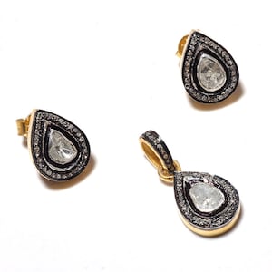 May include: A set of gold and silver teardrop-shaped earrings and pendant with a large, clear, faceted gemstone surrounded by a halo of smaller diamonds.