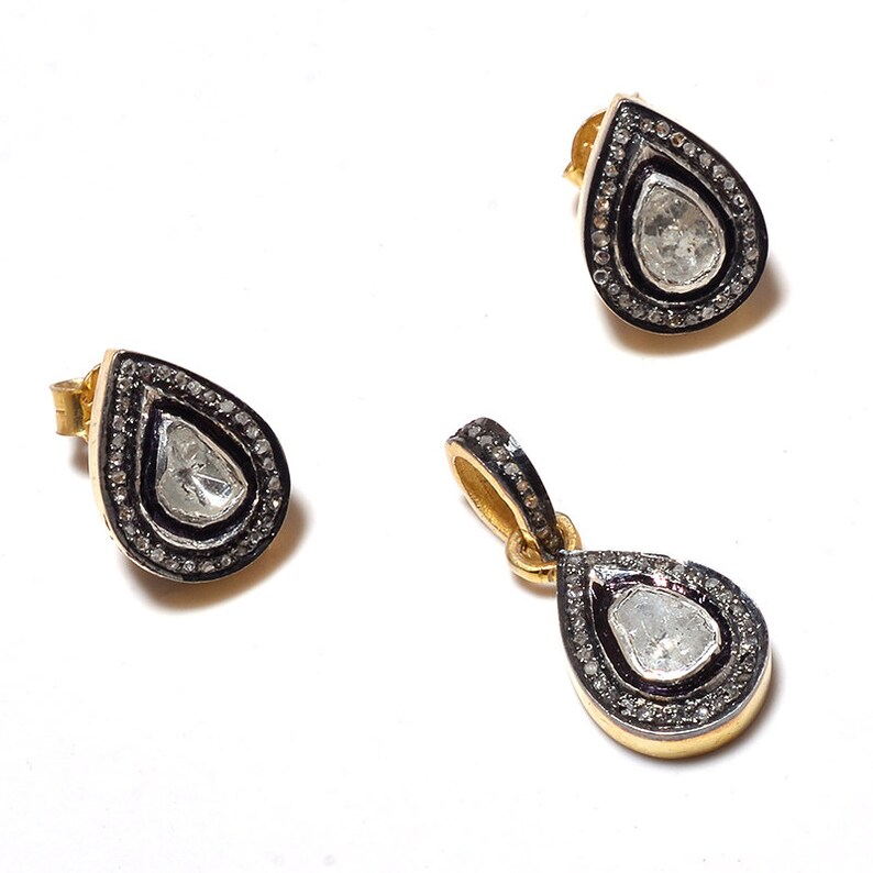 May include: A set of gold and silver teardrop-shaped earrings and pendant with a large, clear, faceted gemstone surrounded by a halo of smaller diamonds.