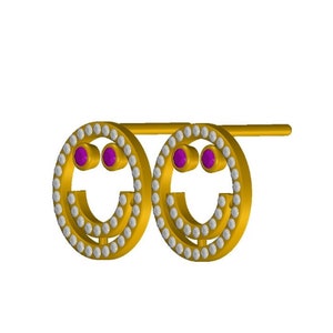 Puede incluir: Pendientes de oro con un diseño de cara sonriente. Los pendientes están decorados con pequeñas piedras blancas y dos piedras rosas para los ojos.