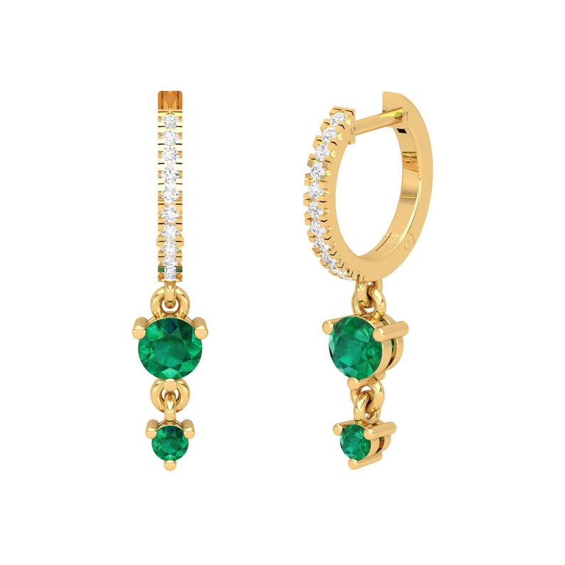 May include: Gold hoop earrings with a dangling emerald green gemstone drop. The hoop is accented with small clear stones.