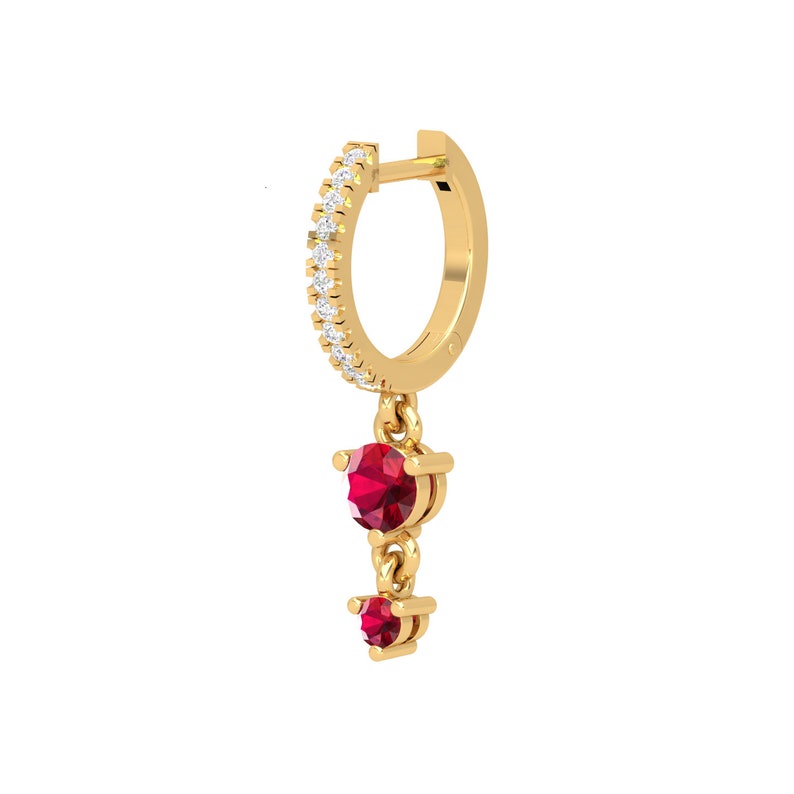 May include: Gold hoop earring with a dangling charm featuring two red gemstones. The hoop is set with small clear stones.