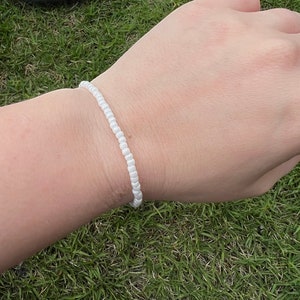 May include: A white beaded bracelet on a person's wrist.