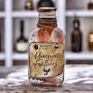Puede incluir: Una botella de vidrio transparente llena de plumas rosas, etiquetada como "Phoenix Feathers". La etiqueta dice "Wizard Pharmacy by East Light Candles". La botella tiene una tapa plateada, envuelta con cuerda, y está sobre una superficie de madera.