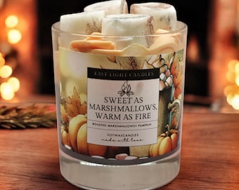 Könnte beinhalten: Eine klare Glas-Kerze mit einem Etikett mit der Aufschrift "Sweet as Marshmallows, Warm as Fire". Die Kerze hat ein Design aus Kürbissen und Herbstblättern. Die Kerze ist mit weißen und hellbraunen Wachswürfeln gefüllt.