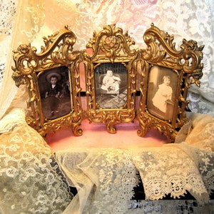 May include: An ornate, three-panel picture frame in a gold tone. Each panel features a black and white photograph of a child.