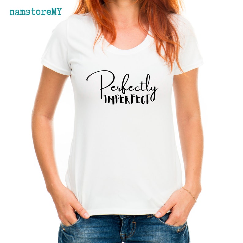 Op de afbeelding: Een wit T-shirt met korte mouwen en de zwarte tekst "Perfectly IMPERFECT" op de borst gedrukt. Het shirt heeft een ronde halslijn en wordt gecombineerd met een blauwe spijkerbroek. De tekst "namstoreMY" staat in de linkerbovenhoek.