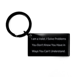 Puede incluir: Llavero de metal negro con una etiqueta rectangular que dice "I am a Valet. I Solve Problems You Don't Know You Have in Ways You Can't Understand."